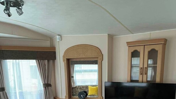 Een woonkamer met een bank, een houten salontafel, een televisie, een open haard en een kast.
