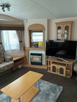 A living room with a sofa, a wooden coffee table, a TV, a fireplace, and a cabinet.