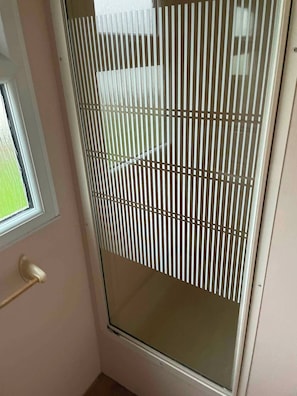 Ein Zimmer mit einer Schiebeglas-Tür, einem Fenster und einer Tür mit Griff.