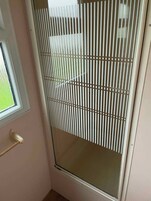 Una habitación con puerta corrediza de vidrio, ventana y puerta con manija.