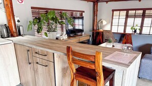 A kitchen with wooden cabinets, a wooden chair, a potted plant, a television, and a table with a menu.