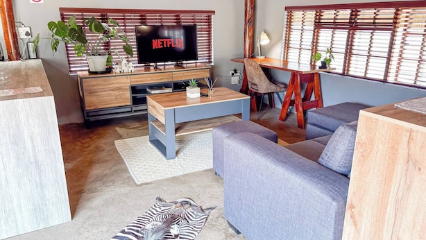 A living room with a TV, sofa, coffee table, and a zebra rug.