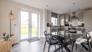 A modern kitchen with a glass dining table, black chairs, and a large window. - Annie Paton Road (No 123) | St Andrews (St Andrews)