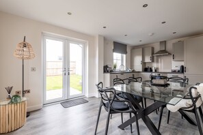 A modern kitchen with a glass dining table, black chairs, and a large window. - Annie Paton Road (No 123) | St Andrews (St Andrews)