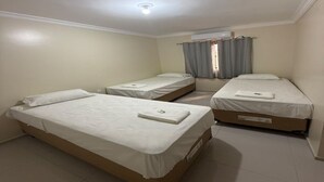 Una habitación con tres camas individuales, una lámpara en el techo, un aire acondicionado y una ventana con cortinas.