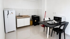 Cocina compacta con refrigerador, pileta, estufa, microondas y mesa de comedor con sillas.