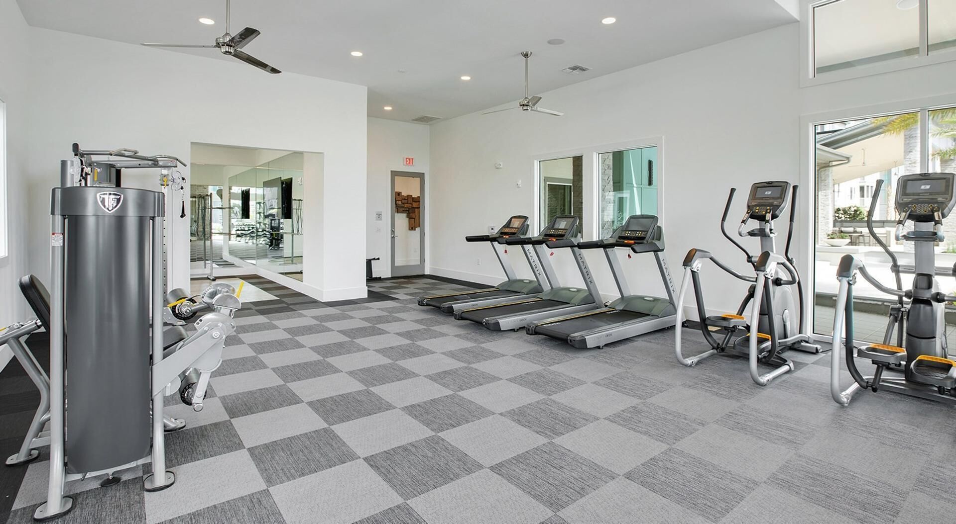 A gym with treadmills, elliptical machines, and a weight machine.