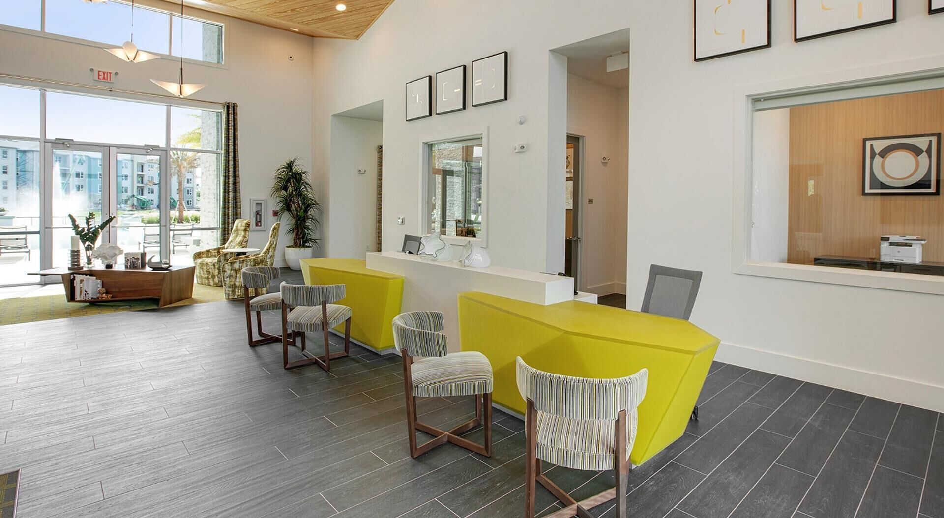 A reception area with a yellow desk, striped chairs, and a large window providing a view of the outside.