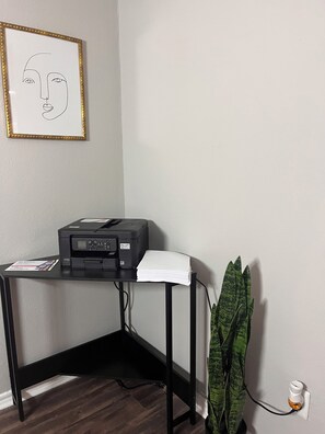 A corner desk with a printer, a framed picture on the wall, and a potted plant. - Stylish Escape/ Walk to Dining & Entertainment (Irving)