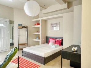 Ein Schlafzimmer mit Bett, Nachttisch, Regalen und einer Tür.