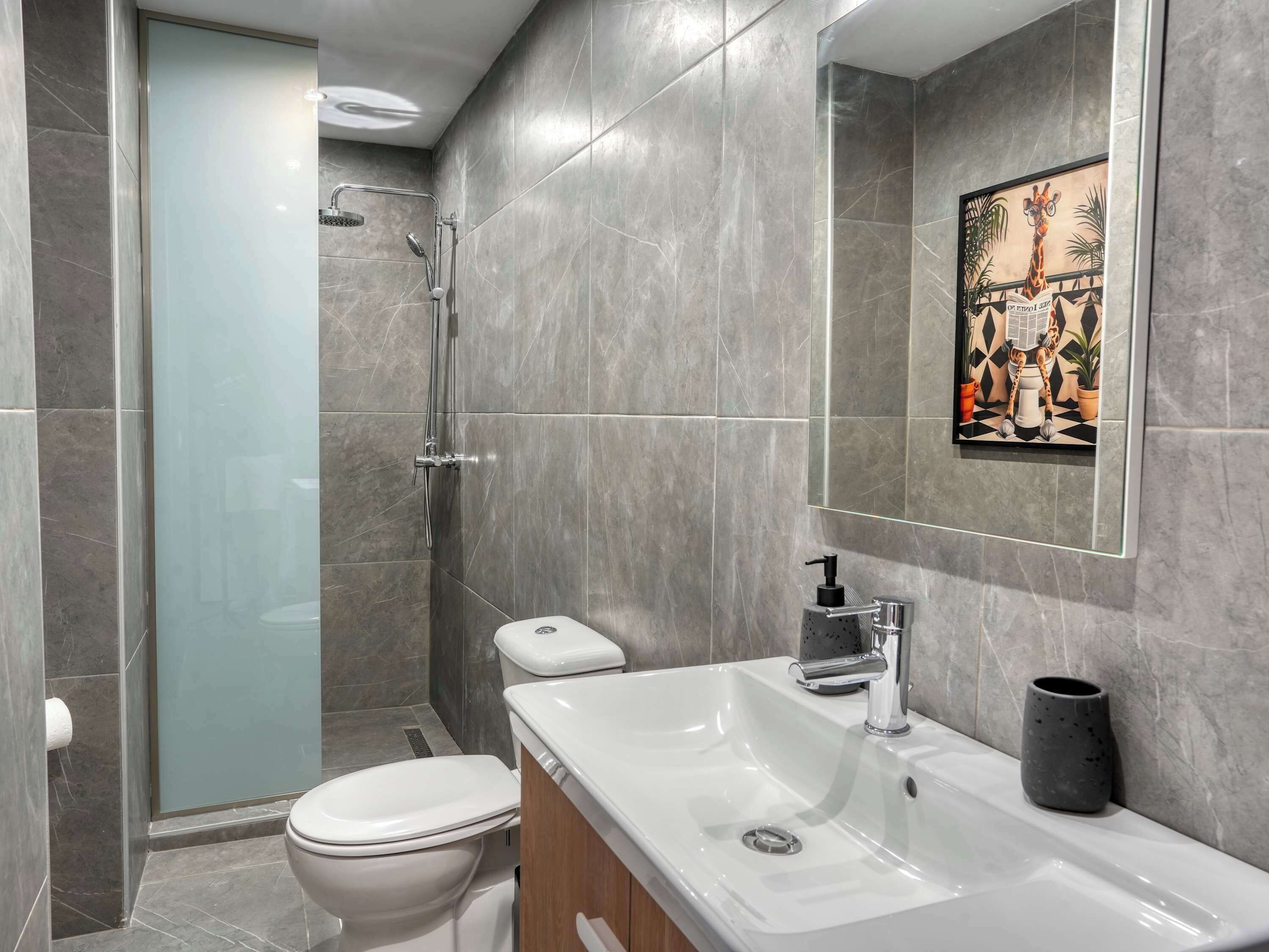 A modern bathroom with a shower, toilet, and sink.
