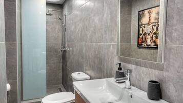 A modern bathroom with a shower, toilet, and sink.