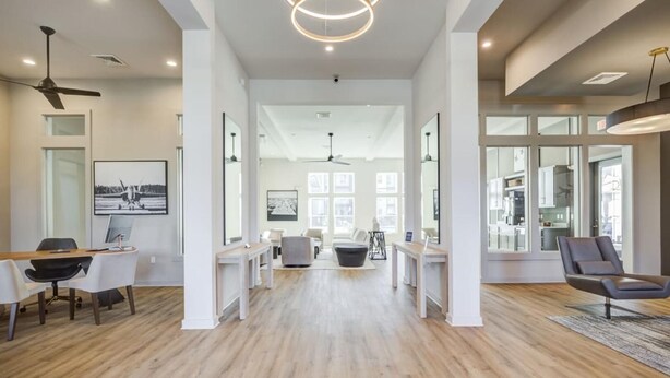 Een ruim interieur met een open middenstuk, witte muren en houten vloeren.
