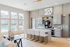 A modern kitchen with a bar area, large windows, and a view of a swimming pool. - Landing Modern 1BD in Warrington (Pensacola)