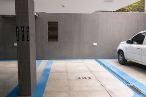 Ein Parkplatz mit nummerierten Stellplätzen, ein weißes Auto parkiert und eine blaue Linie, die die Parkplatzbegrenzung markiert.