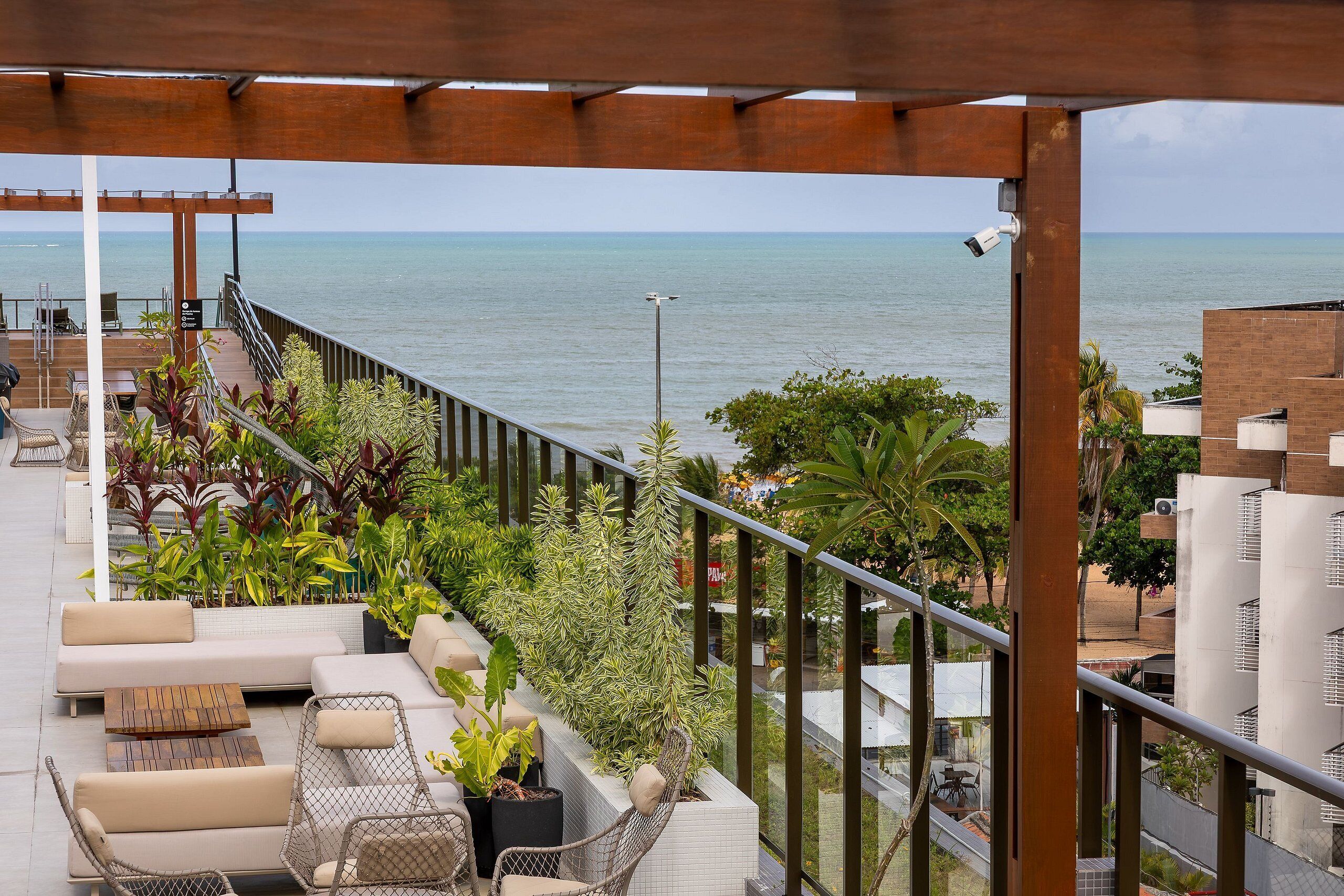 A balcony with outdoor seating, a view of the sea, and a security camera.