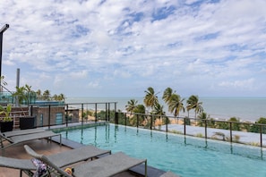 A rooftop infinity pool with lounge chairs, palm trees, and a view of the ocean. - Jardins Almares #325 - Cabo Branco by Carpediem (João Pessoa)