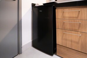 Ein schwarzer Kühlschrank neben einem Holzkasten mit drei Schubladen.
