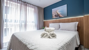 A hotel room with a large bed, a painting of a coastal city, and sheer curtains. - Jardins Almares #325 - Cabo Branco by Carpediem (João Pessoa)