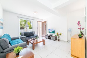 A modern living room with a sofa, coffee table, TV, and a wooden cabinet. - Villa Avra 84 in Protaras (Paralimni)