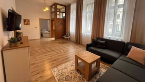 Ein modernes Wohnzimmer mit einer Couch, einem Couchtisch und einem an der Wand montierten Fernseher.
