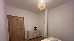 Ein Schlafzimmer mit Holztür, einem Schrank, einer hohen weißen Säule und einem Bett mit einem gerollten Handtuch.