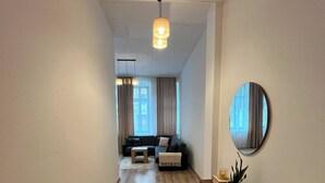 Ein modernes Wohnzimmer mit einer Couch, einem Couchtisch, einem runden Spiegel und Holzboden.