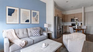 A modern living room with a sofa, coffee table, and a dining area with a chair. - Landing Apartments Houston along Washington Ave (Houston)