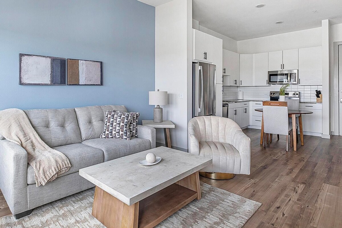 A modern living room with a sofa, coffee table, and a dining area with a chair and table.