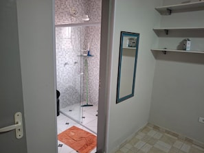 A bathroom with a glass shower enclosure, a towel on the floor, and a mirror on the wall. - Cozy house 5 minutes from Massaguaçu Beach (Caraguatatuba)