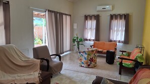 A living room with a sofa, armchairs, a coffee table, and a TV.