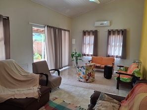 A living room with a sofa, armchairs, a coffee table, and a TV. - Cozy house 5 minutes from Massaguaçu Beach (Caraguatatuba)