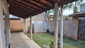 A covered patio area with a tiled floor, a grassy yard, and a brick wall.