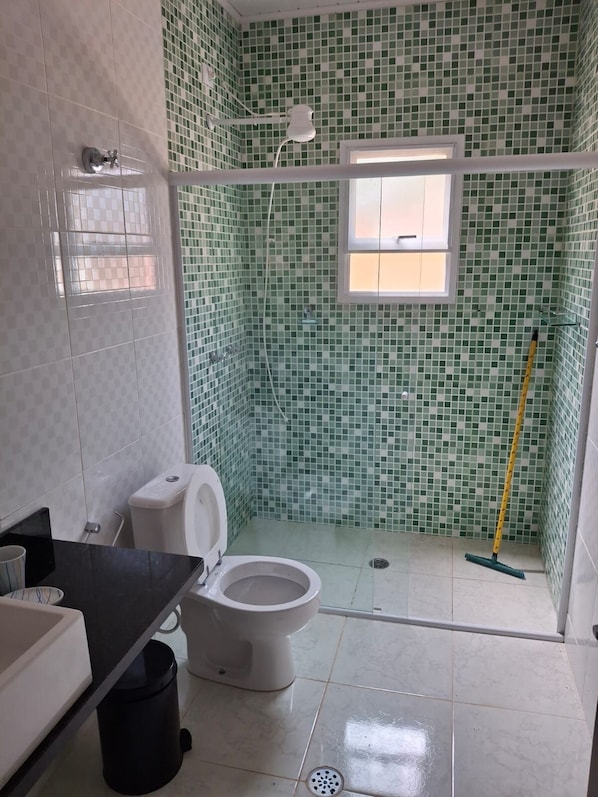 A bathroom with a toilet, a shower, and a sink.