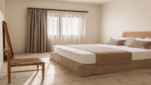 A bedroom with a bed, a chair, a window with curtains, and a ceiling light. - Lanu sea view apartment (Argostoli)