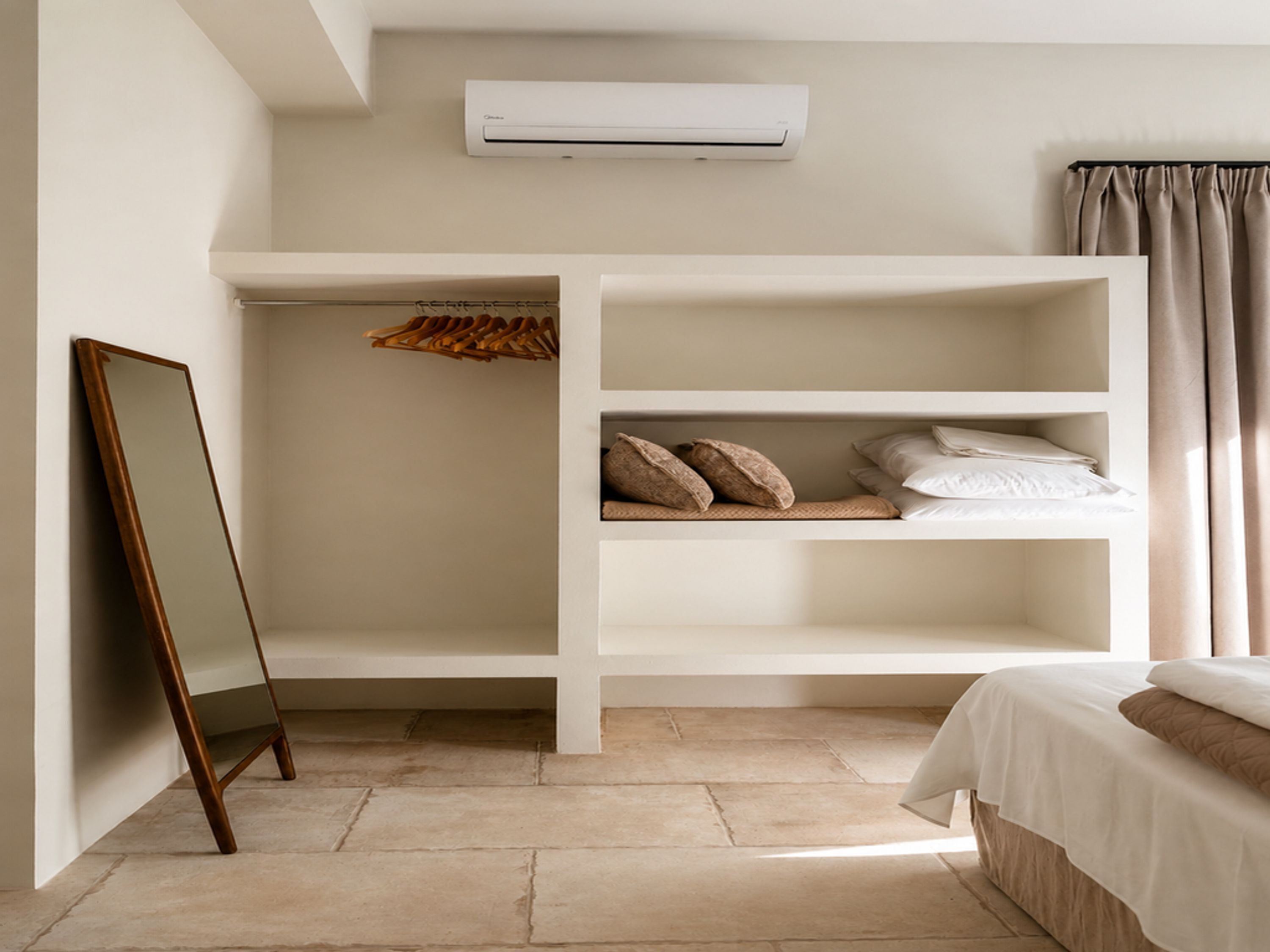 Una camera da letto con un letto, un armadio, uno specchio e un condizionatore d'aria.