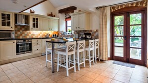 Una cucina con isola centrale, sedie bianche, forno integrato e un'ampia finestra.