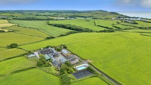 Vista aerea di una tenuta rurale con campi, una piscina e un edificio grande diviso in più sezioni.