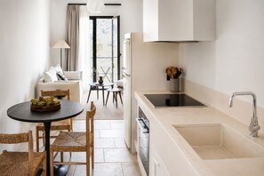 A modern kitchen with a sink, stove, and dining area with chairs and a table. - Lanu Sea View Studio (Argostoli)