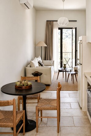 A modern living room with a round table, wicker chairs, a sofa, and a dining area with a small table and chairs. - Lanu Sea View Studio (Argostoli)