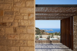 Eine Steinsäule und ein Holz-Pergola mit Blick auf das Meer.