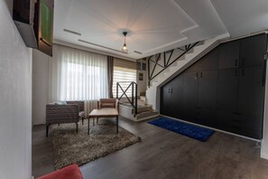 En moderne stue med sofa, sofabord, trappe og garderobeskab.