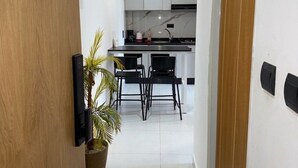 Cozinha moderna com armários brancos, bancada preta e iluminação pendente.