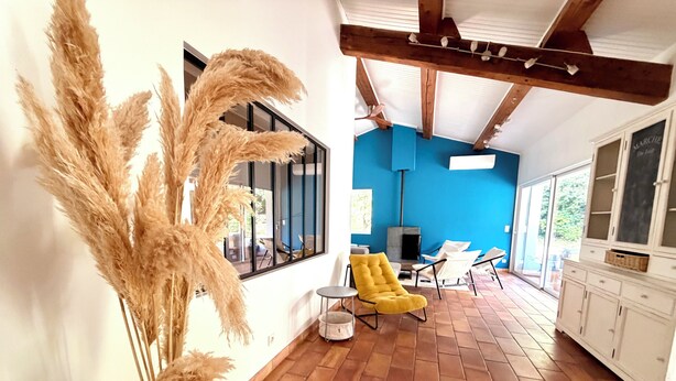 Quarto com parede azul, piso de madeira, uma cadeira amarela e uma janela grande.