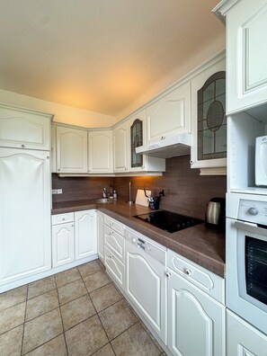 A kitchen with white cabinetry, a built-in oven, and a microwave. - The Grand Polo • Deauville • 4 bedrooms • Downtown on foot (Deauville)