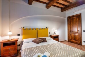 A bedroom with a bed, wooden nightstands, a wardrobe, and a curved ceiling. - GuestHost - Il Casale dei Gelsi - Biancospino (San Martino In Campo)