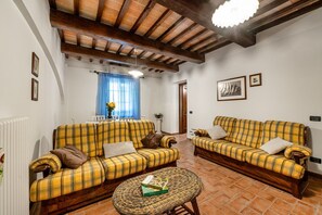 A living room with two yellow plaid sofas, a wicker coffee table, and a ceiling with exposed wooden beams. - GuestHost - Il Casale dei Gelsi - Biancospino (San Martino In Campo)