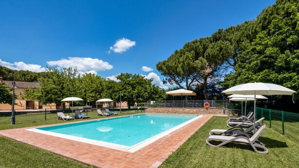 A rectangular swimming pool with a tiled border, surrounded by grass, and shaded by umbrellas. - GuestHost - Il Casale dei Gelsi - Biancospino (San Martino In Campo)