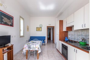 Una cocina compacta con comedor, televisión y un mapa en la pared.
