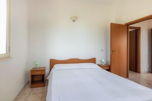 Ein Schlafzimmer mit einem Bett, Nachttischen, einer Tür und einer Lampe.